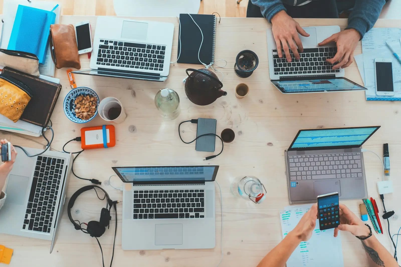 Ein Team arbeitet gemeinsam mit Laptops an einem langen Tisch