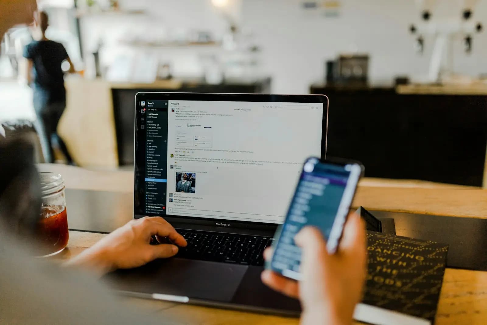 Eine Person nutzt einen Online-Dienst am Laptop und prüft dabei ihr Smartphone