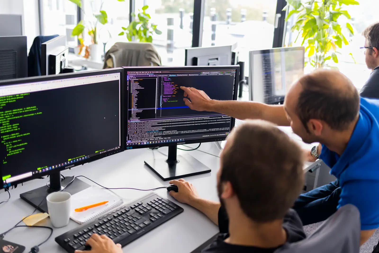 Zwei Kolleg:innen beim Pair Programming am Schreibtisch